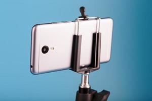 smartphone på en stativ som en foto-video kamera på en blå bakgrund. spela in videoklipp och foton för din blogg.