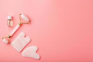 gua sha massage verktyg tillverkad av naturlig rosa kvartsvals, jade sten och olja, på en rosa bakgrund för ansikte och kropp vård. del av traditionell kinesisk medicin foto