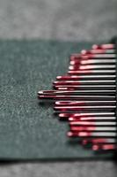 sömnad nålar av annorlunda storlekar i en uppsättning av röd på en svart bakgrund. foto