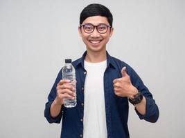 asiatisk man Lycklig leende håll vatten flaska och tumme upp isolerat foto