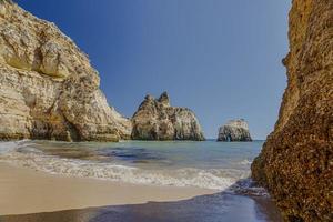 se på typisk klippigt strand på algarve kustlinje i portugal i sommar foto