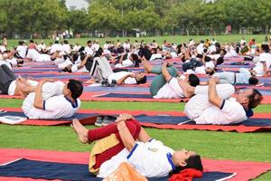 ny delhi, Indien, juni 21 2022 - grupp yoga övning session för människor på yamuna sporter komplex i delhi på internationell yoga dag, stor grupp av vuxna delta yoga klass i cricket stadion foto