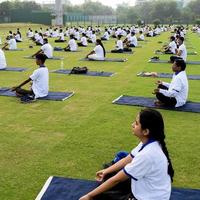 ny delhi, Indien, juni 21 2022 - grupp yoga övning session för människor på yamuna sporter komplex i delhi på internationell yoga dag, stor grupp av vuxna delta yoga klass i cricket stadion foto