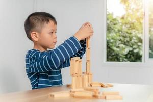 pojke leker med träklossar hemma foto
