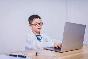 asiatisk pojke läkare använder sig av en bärbar dator dator foto
