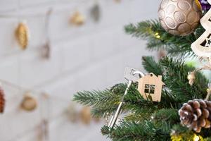 nyckeln till huset med en nyckelring hänger på julgranen. en present till nyår, jul. bygga, designa, projektera, flytta till nytt hus, belåna, hyra och köpa fastigheter. kopieringsutrymme foto