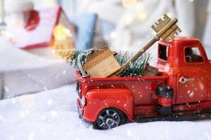 röd retro bil med en jul träd dekorerar med de hus nyckel i de plocka upp lastbil för jul. uppköp en Hem, rör på sig, inteckning, lån, verklig egendom, festlig humör, ny år foto
