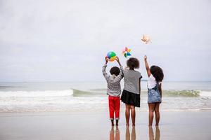 tillbaka sida av afrikansk amerikan barn stående på en tropisk strand. etniskt olika begrepp foto