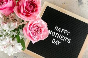 Lycklig mors dag text på svart brev styrelse och rosa rosor, Gypsophila alstroemeria. platt lägga foto