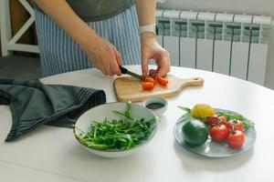 kvinna framställning vegetabiliska sallad med tomat i de kök. friska mat vegan sallad. uppmärksam äter foto