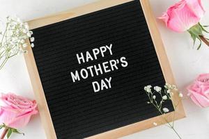 Lycklig mors dag text på svart brev styrelse. rosa rosor, Gypsophila på bakgrund. foto