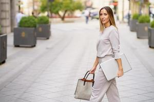 eleganta kvinna entreprenör med netbook promenader på stad gata foto