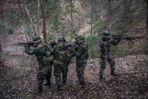 team av armésoldat med maskingevär som rör sig i skogen, thailändsk milissoldat i stridsuniformer i skogen, vandra patrullen som sluttar i regnskogen. foto