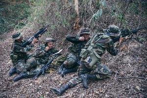 team av armésoldat med maskingevär som rör sig i skogen, thailändsk milissoldat i stridsuniformer i skogen, vandra patrullen som sluttar i regnskogen. foto