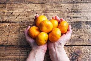 apelsiner mandariner eller mandariner clementiner, citrus- frukt i en kvinnors händer på en trä- tabell. foto