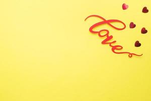 de ord kärlek och röd hjärtan på en gul bakgrund, topp se. Semester kort för hjärtans dag. platt lägga. foto