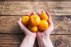 apelsiner mandariner eller mandariner clementiner, citrus- frukt i en kvinnors händer på en trä- tabell. foto