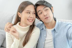 asiatisk par är njuter ny Hem och tar selfies tillsammans. Tonårs Make och fru efter äktenskap. lycka och ler och skratt i värma familj. gosa, värma kramar, tonåringar först kärlek foto
