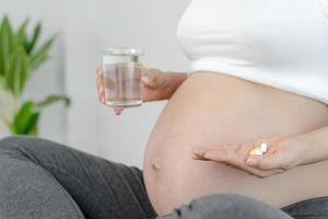 gravid kvinnor ta vitaminer och dricka vatten till uppföda ofödd barn. tar läkemedel eller vitaminer, graviditet kvinnor måste upprätthålla de näring behövs för fysisk utveckling. uppföda, nödvändig. foto