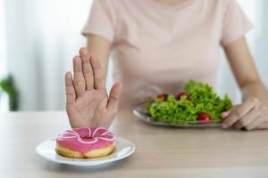 Bra hälsa mat och diet. kvinnor avvisa skräp mat eller ohälsosam livsmedel sådan som munkar och välja friska livsmedel sådan som grön äpple. foto