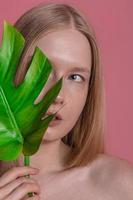 skön kvinna med en slät hud innehav grön tropisk blad foto