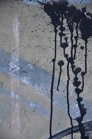 en fotografera av en närbild av svart måla fläckar på en betong vägg. häller måla på de vägg i slumpmässig ordning. de begrepp av graffiti och gata konst kultur foto