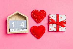 topp se av trä- kalender, vit gåva lådor och röd textil- hjärtan på färgrik bakgrund. hjärtans dag begrepp foto