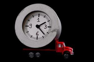 miniatyr- lastbil bärande en klocka på svart bakgrund foto