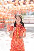 vertikal bild. Lycklig kinesisk ny år. en ung lady bär traditionell Cheongsam qipao klänning innehav välsignelse förmögenhet kort i kinesisk buddist tempel. kinesisk text betyder välsignad förbi en tur- stjärna. foto