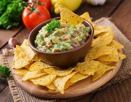 guacamole avokado, lime, tomat, lök och koriander, serveras med nachos - traditionellt mexikanskt mellanmål foto