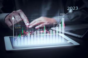 finansiell diagram och Graf analys marknadsföring som visar växande inkomst i 2023 flytande ovan digital skärm läsplatta, företag handla om strategi för tillväxt och framgång.investering i stock marknader medel. foto