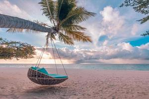 tropisk strand solnedgångslandskap med strandgunga eller hängmatta och solnedgångshimmel vit sand och lugnt hav för strandbanner. perfekt strand scen semester och sommar semester koncept. öka färgprocessen foto