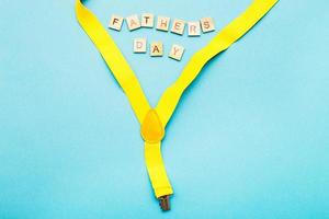 Lycklig fars dag text tillverkad förbi trä- kuber på en blå bakgrund med en gul hängslen foto