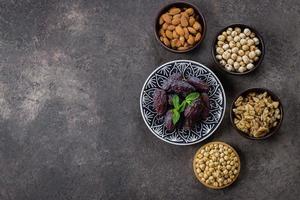 ramadan mat bakgrund. färsk datum och nötter i skålar på mörk betong bakgrund. ramadan kareem. foto