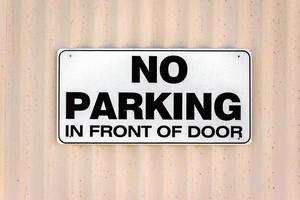 Nej parkering i främre av dörr tecken foto