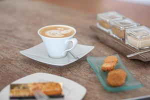 kaffe kopp med choklad kaka på ljus trä- bakgrund. kopp av cappuccino kaffe på trä- tabell. foto