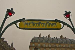 paris metro metropolitan tecken nära louvre under snö flingor foto