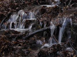 små strömmande flod på grund av till snö smälta formning en rena kaskad med färsk Häftigt vatten omgiven förbi vegetation berg foto