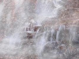 små strömmande flod på grund av till snö smälta formning en rena kaskad med färsk Häftigt vatten omgiven förbi vegetation berg foto