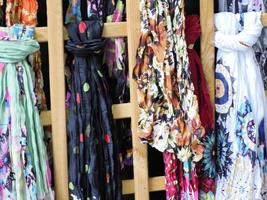 färgrik årgång halsdukar med annorlunda mönster, färger och texturer hängande på en kuggstång på ett utomhus- affär foto