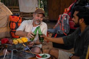 grupp turister vänner camping och har en utegrill och dricka öl-alkohol och krascha en öl flaska med de fest tillsammans med njutning och lycka i sommar foto