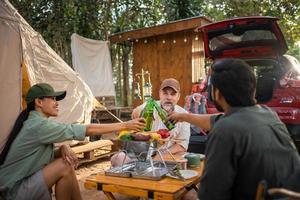 grupp turister vänner camping och har en utegrill och dricka öl-alkohol och krascha en öl flaska med de fest tillsammans med njutning och lycka i sommar foto