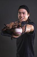 asiatisk manlig modell med baseboll handske isolerat på mörk bakgrund. baseboll spelare begrepp foto