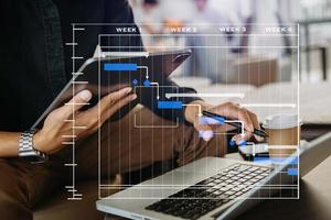 projektledare som arbetar och uppdaterar uppgifter med milstolpar framstegsplanering och Gantt-diagram schemaläggningsdiagram. företag som arbetar med smart telefon, surfplatta och bärbar dator foto