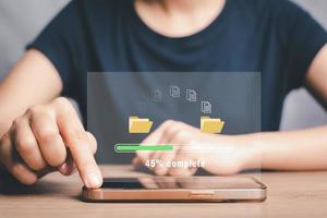 överföra filer data systemet omlokalisering begrepp, person hand använder sig av smart telefon till väntar för överföra fil bearbeta med läser in bar ikon på virtuell skärm. foto