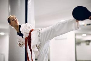 kvinna taekwondo kämpe utan de övre lemmar utövar ben sparka med en tränare i hälsa klubb. foto