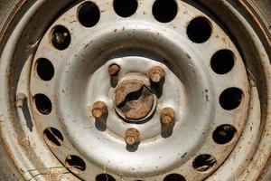 gammal rostig hjul i de solljus. hjul fälg, bultar och capped schrader ventil. närbild foto