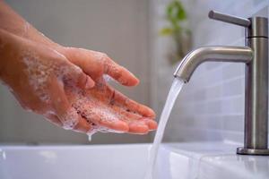 tvätta din händer med tvål, förhindra virus och bakterie i de kran med löpning vatten. Bra hygien innan äter eller hantering offentlig objekt foto