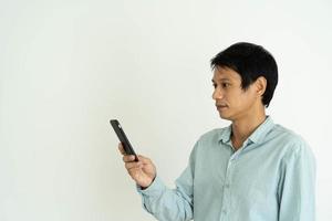 asiatisk man är chockade medan ser på en mobil telefon. män do ansiktsbehandling uttryck, överraskning meddelanden eller saker den där dyka upp på deras telefoner. foto