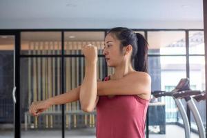 asiatisk kvinnor bär sportkläder stående, stretching vapen, framställning muskler till sträcka till förbereda de kropp till vara redo till träning. hälsa och kondition begrepp foto